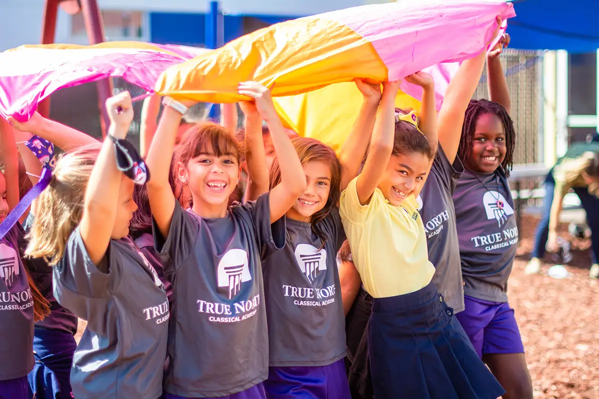 Students playing together outdoors in True North Classical Academy shirts